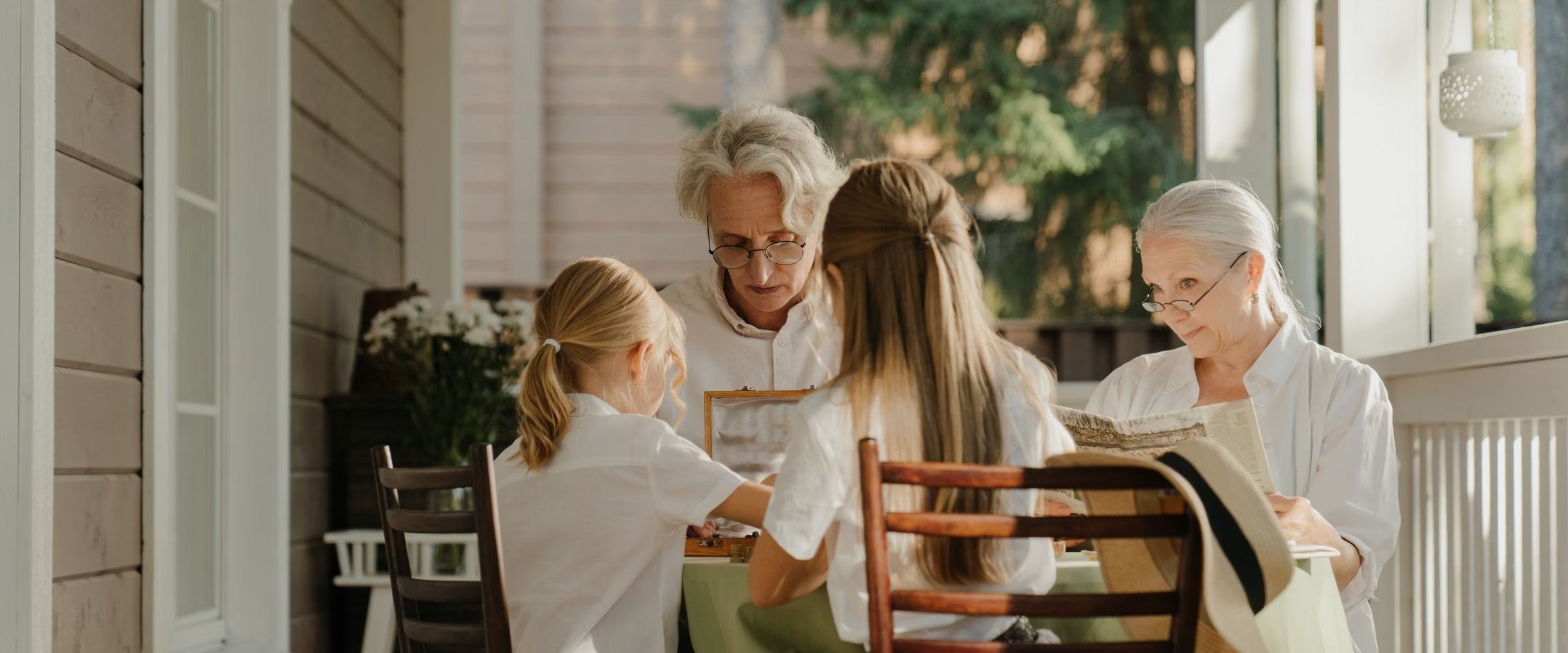 Grandparents and granddaughters sharing an afternoon at a table on a sunny porch